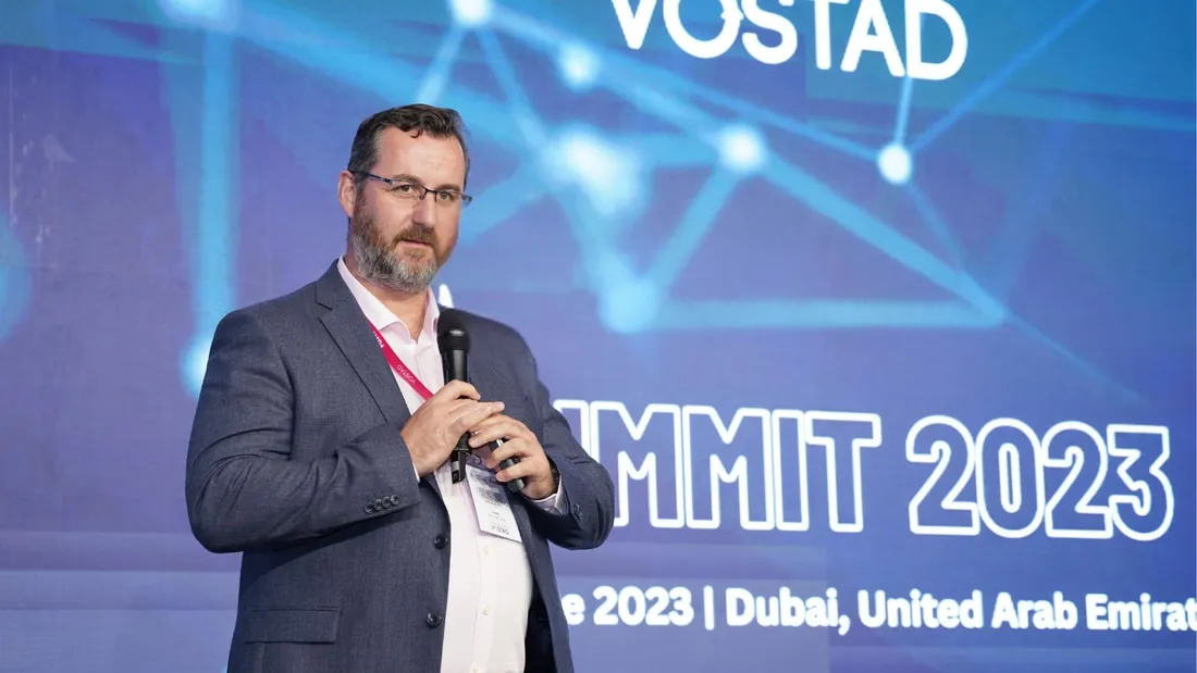 A speaker addressing the room with a microphone at a previous summit