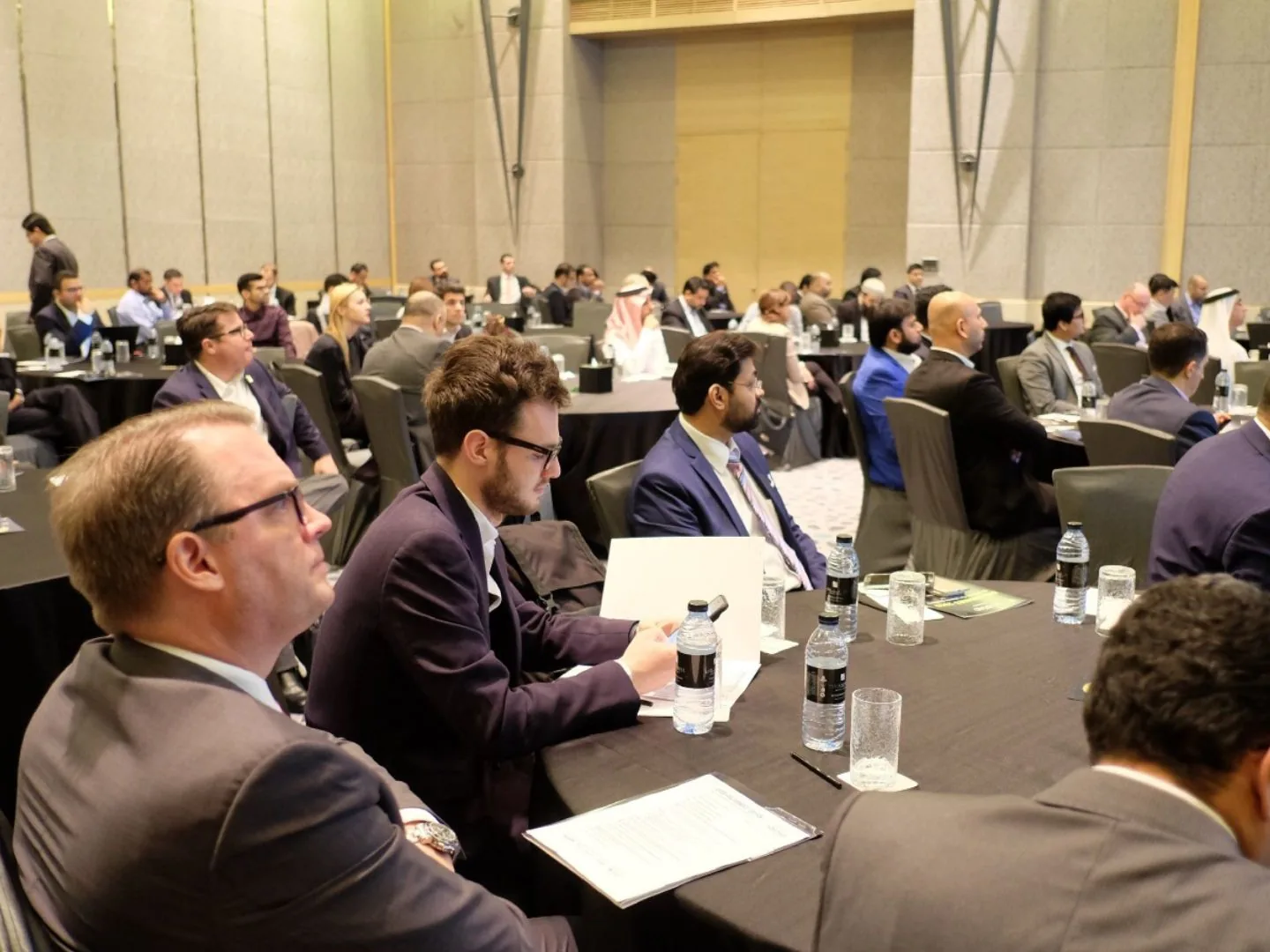 Delegates seated at round tables during a conference session