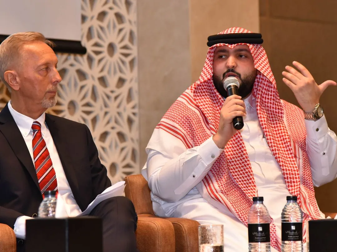Two speakers in conversation on a conference stage